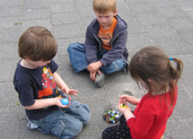 A group of 3 children playing marbles